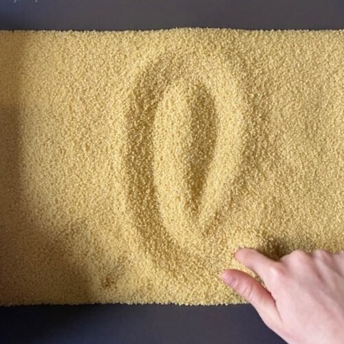 Tas de semoule jaune avec un symbole dessiné par une main sur la surface.